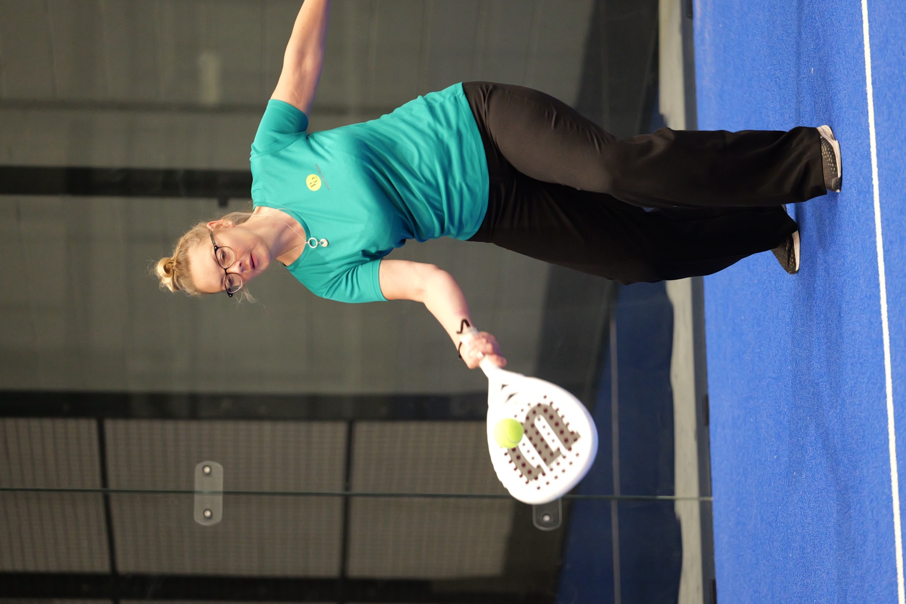 A player stretching for a low ball on Padel Quarter’s blue courts